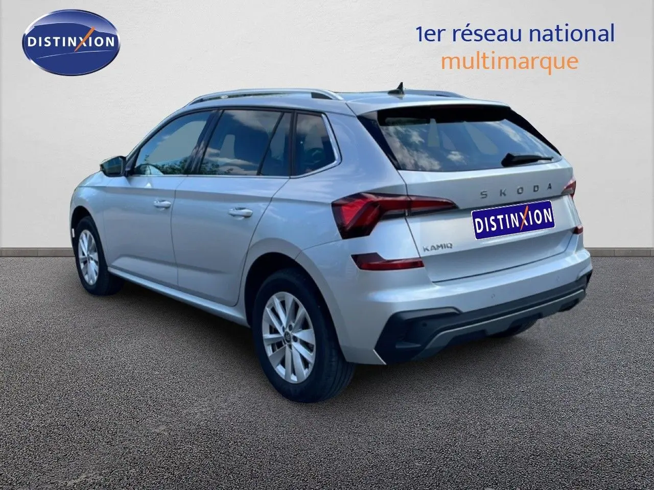 Vue 3/4 arrière droite d'un Skoda Kamiq gris argent métallisé avec feux arrière LED et toit avec barres de toit.