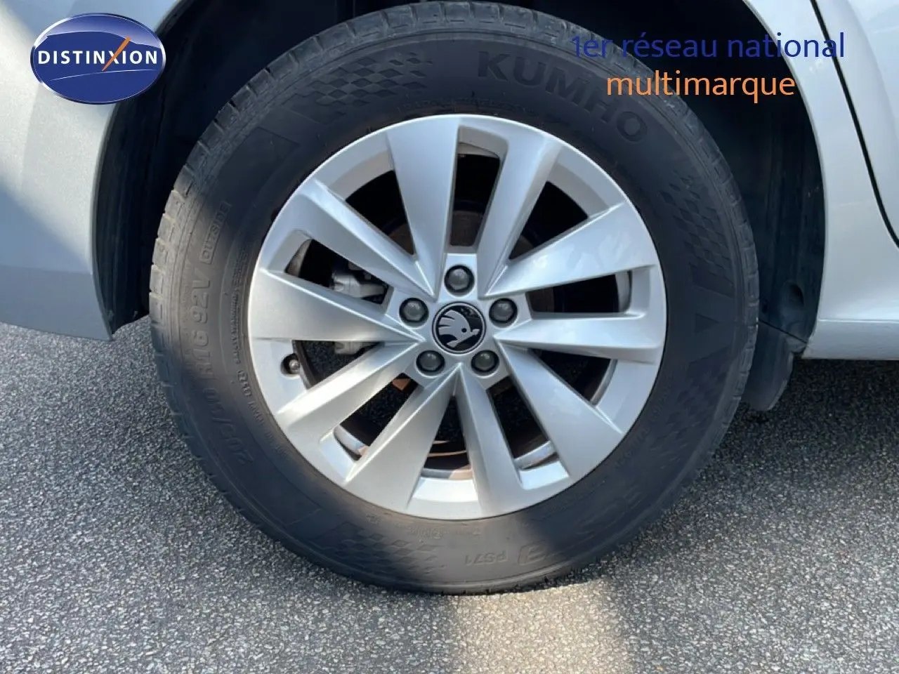 Gros plan sur la roue avant droite d’un Skoda Kamiq gris argent métal avec jante alliage et logo central visible.