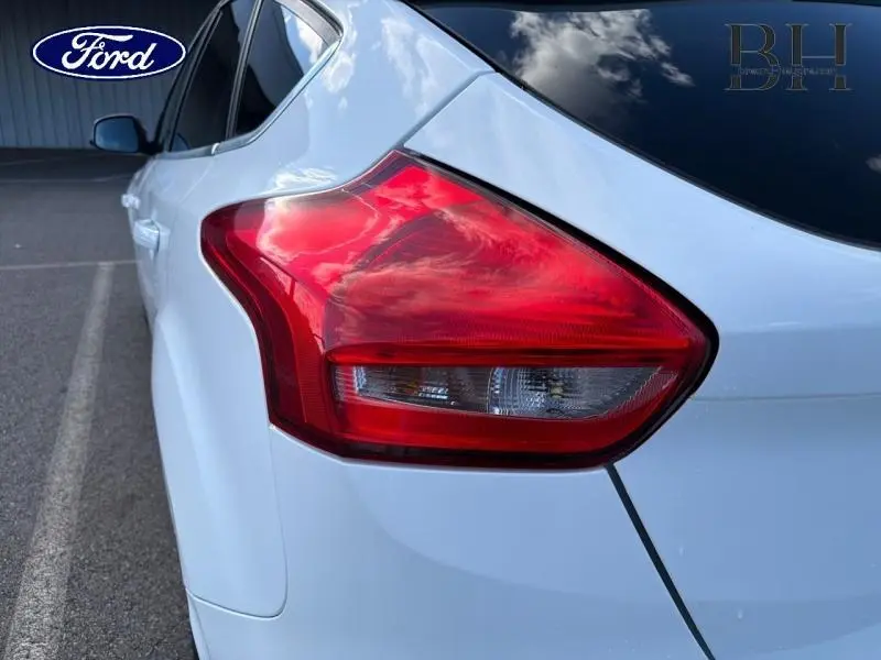 Gros plan sur le feu arrière droit d'une Ford Focus blanc glacier, avec vitre arrière surteintée visible.