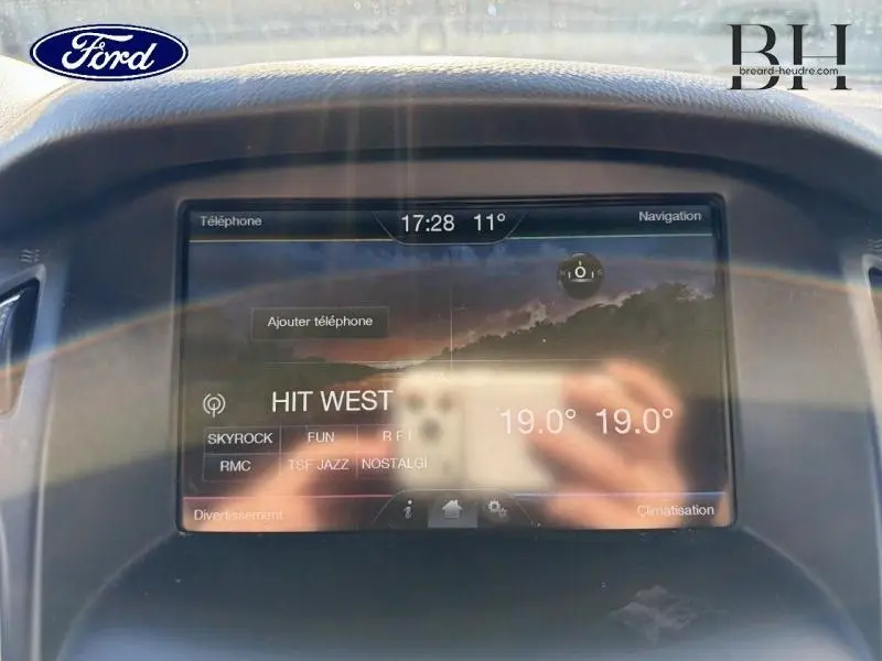 Écran tactile central de la Ford Focus blanc Glacier 2016 affichant la radio et la température intérieure.