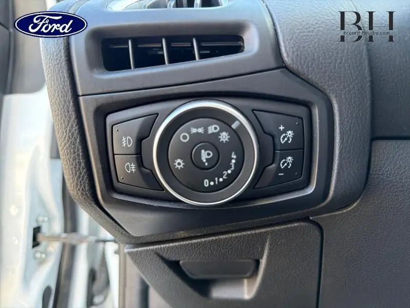 Gros plan sur le bouton de réglage des phares et des éclairages intérieurs d'une Ford Focus blanche, côté conducteur.