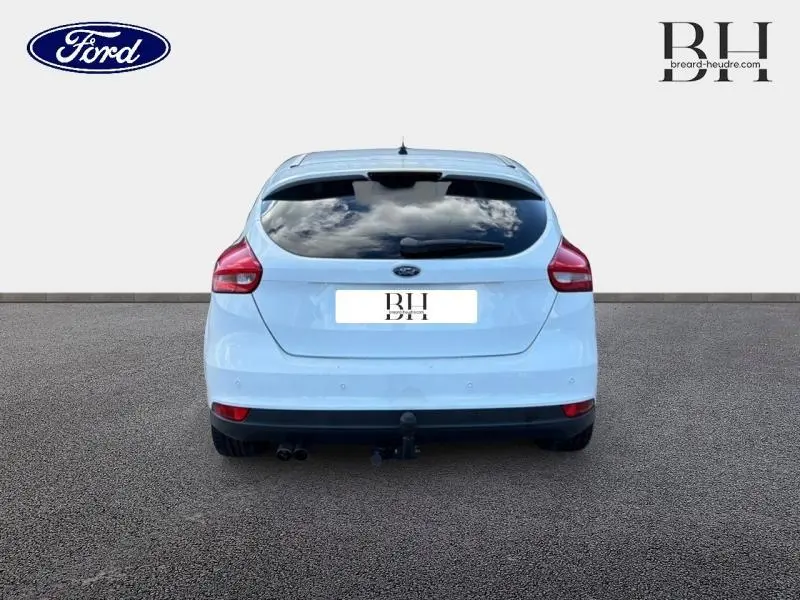 Vue arrière d'une Ford Focus blanche Glacier 2016 avec vitres arrière surteintées et attelage visible.