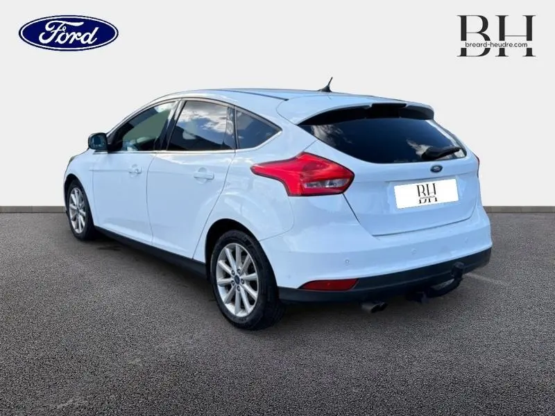 Ford Focus blanc glacier vue 3/4 arrière droit avec vitres arrière surteintées et jantes alu.
