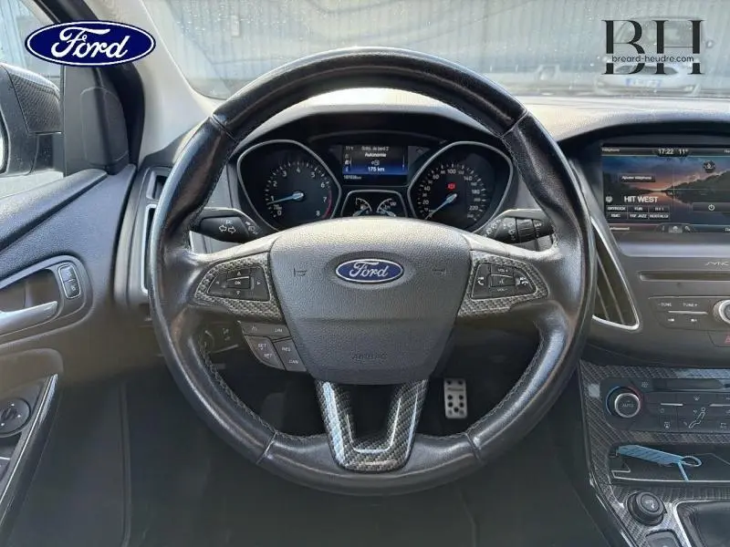 Vue intérieure centrée sur le volant cuir multifonction de la Ford Focus Titanium 2016 avec tableau de bord et écran tactile.