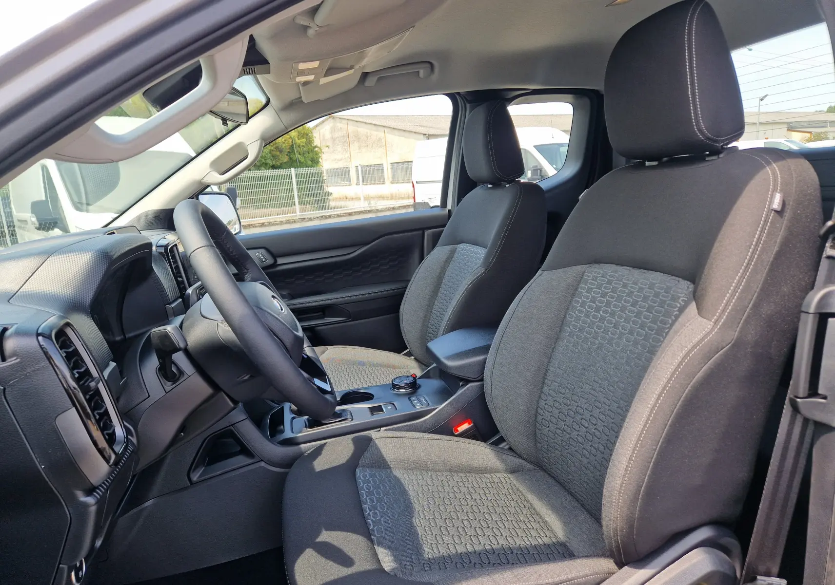 Vue intérieure côté conducteur du Ford Ranger Super Cabine gris Iconic, montrant les sièges avant et le tableau de bord.