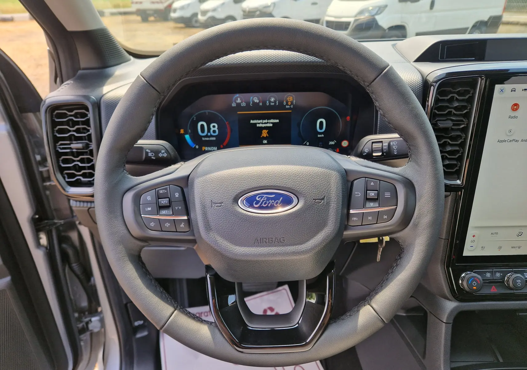 Vue intérieure centrée sur le volant du Ford Ranger Super Cabine gris Iconic, avec tableau de bord numérique et écran tactile.