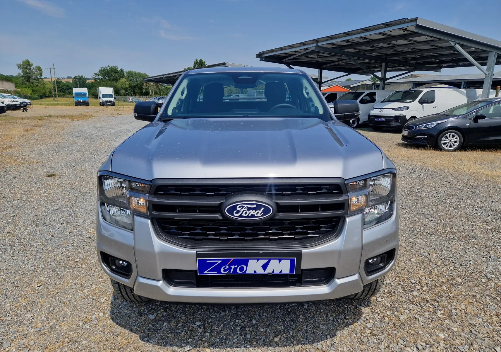 Vue frontale d'un Ford Ranger Super Cabine gris iconic avec calandre noire et plaque d'immatriculation Zéro KM.