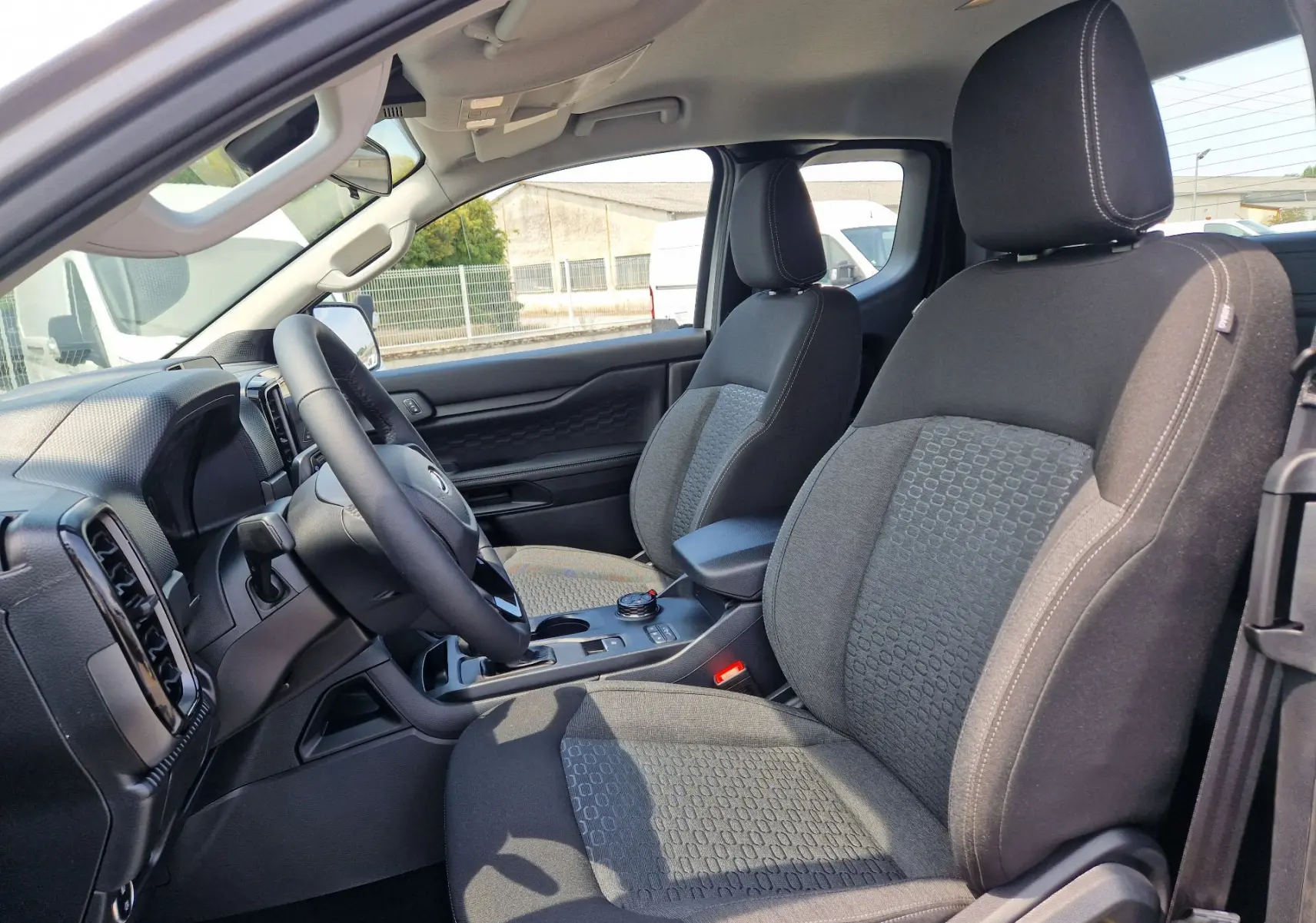 Vue intérieure côté conducteur du Ford Ranger Super Cabine gris Iconic, montrant les sièges avant et le tableau de bord.