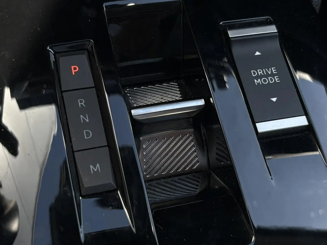 Gros plan sur la console centrale noire brillante avec commandes de boîte auto et bouton Drive Mode de la Citroën C4 Hybrid 2025.