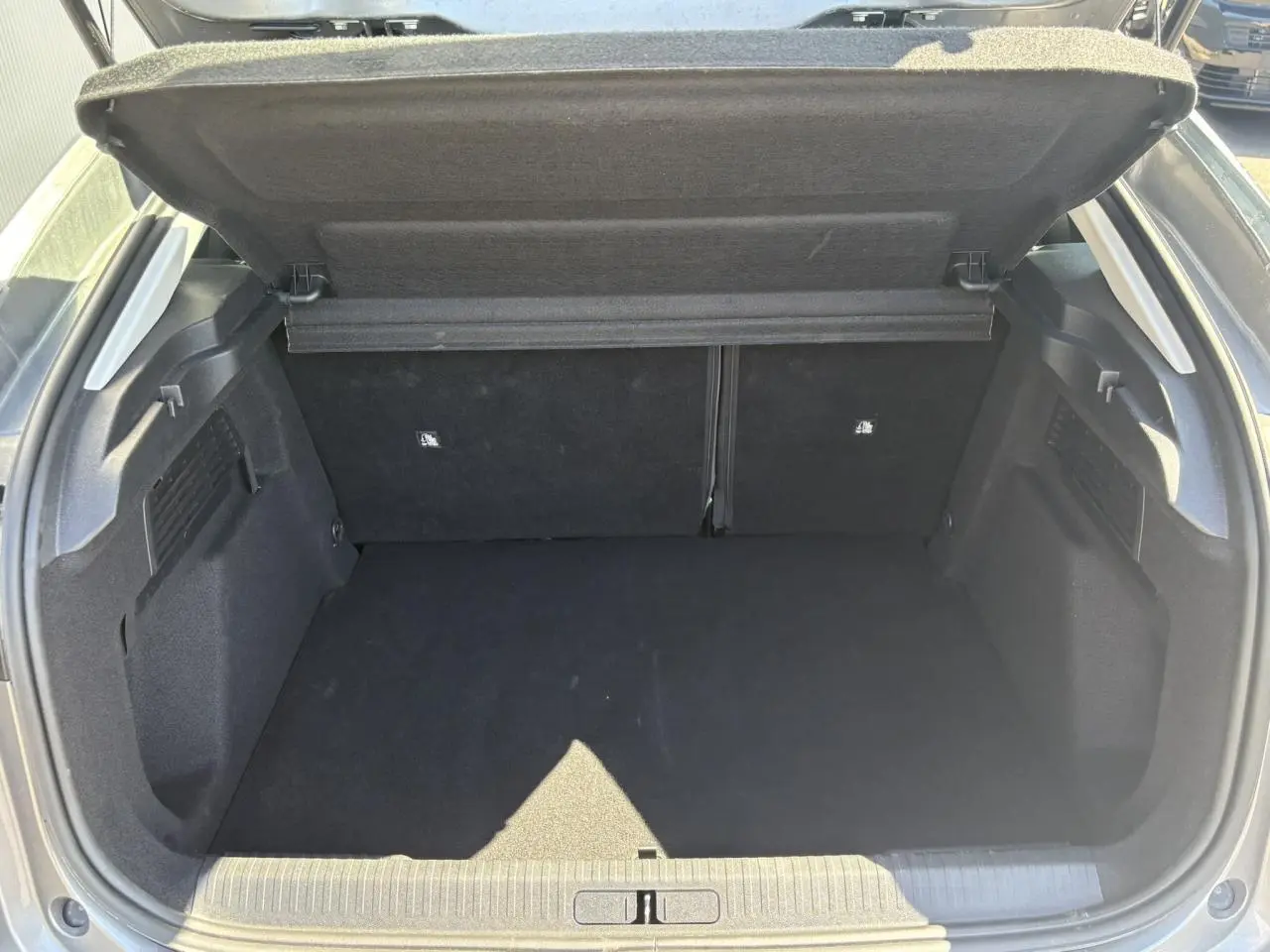 Coffre ouvert vu de l'arrière d'une Citroën C4 Hybrid 145 gris Mercury, espace de chargement vide et propre.