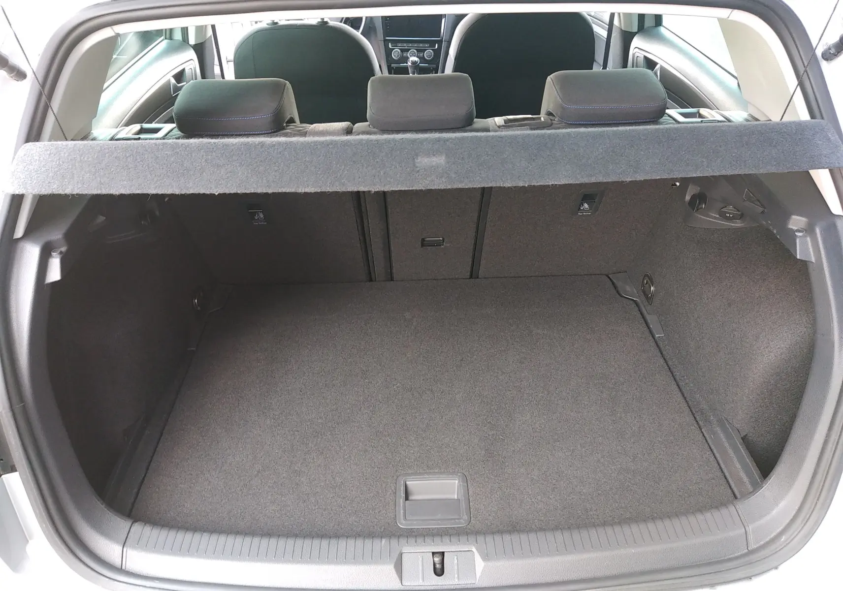 Vue du coffre ouvert d'une Volkswagen Golf gris reflet d'argent, montrant l'espace de chargement et la banquette arrière.