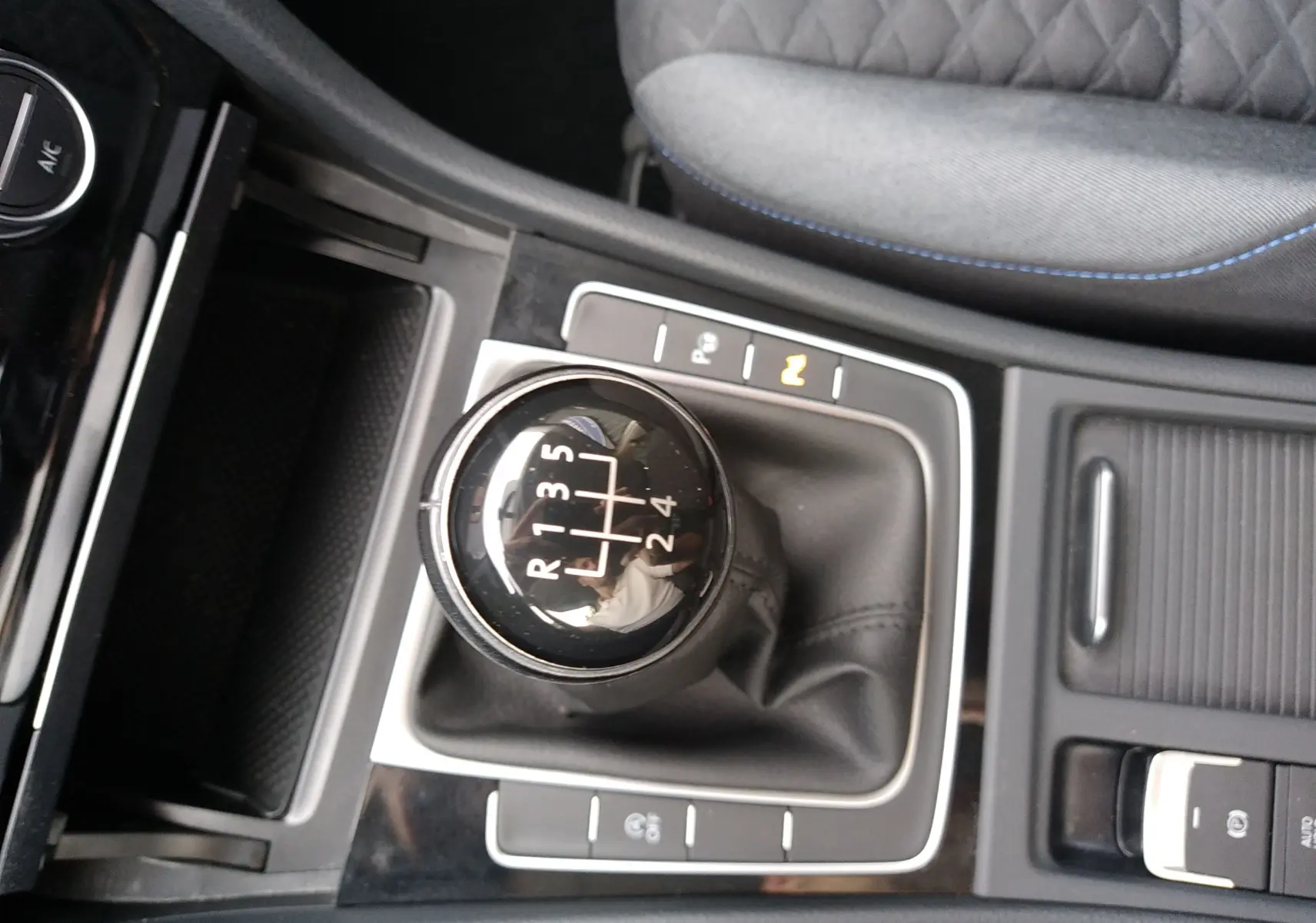 Vue rapprochée de la commande de boîte manuelle noire de la Volkswagen Golf 1.6 TDI 2019 avec coutures bleues sur siège tissu gris.
