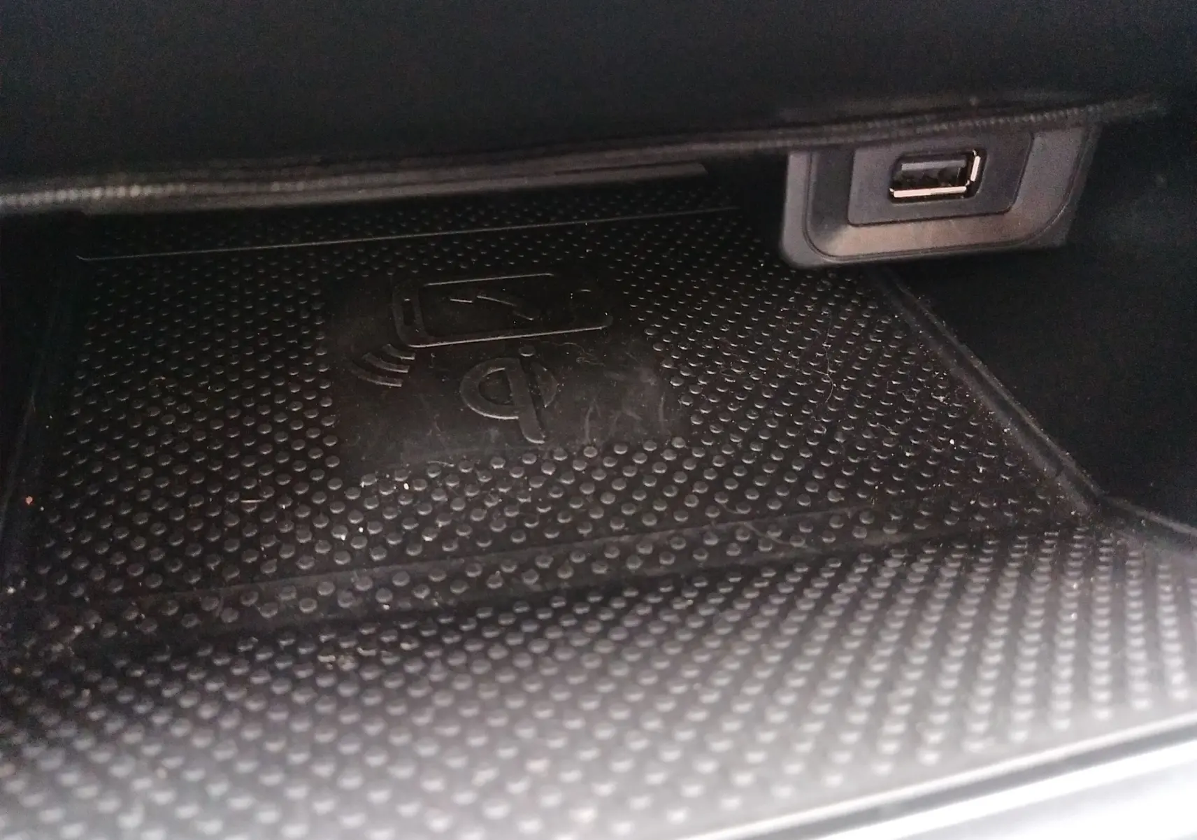 Gros plan sur le compartiment intérieur avec zone de charge sans fil Qi et port USB de la Volkswagen Golf gris reflet d'argent.