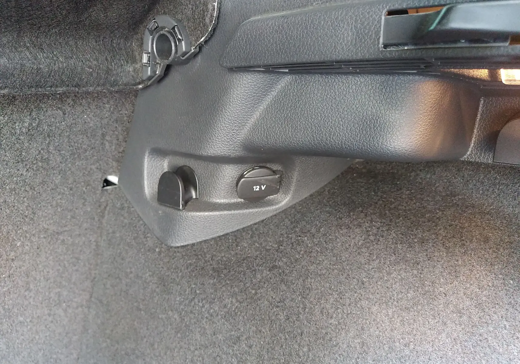 Détail de la prise 12V et prise accessoire dans le coffre d'une Volkswagen Golf gris reflet d'argent, vue intérieure.