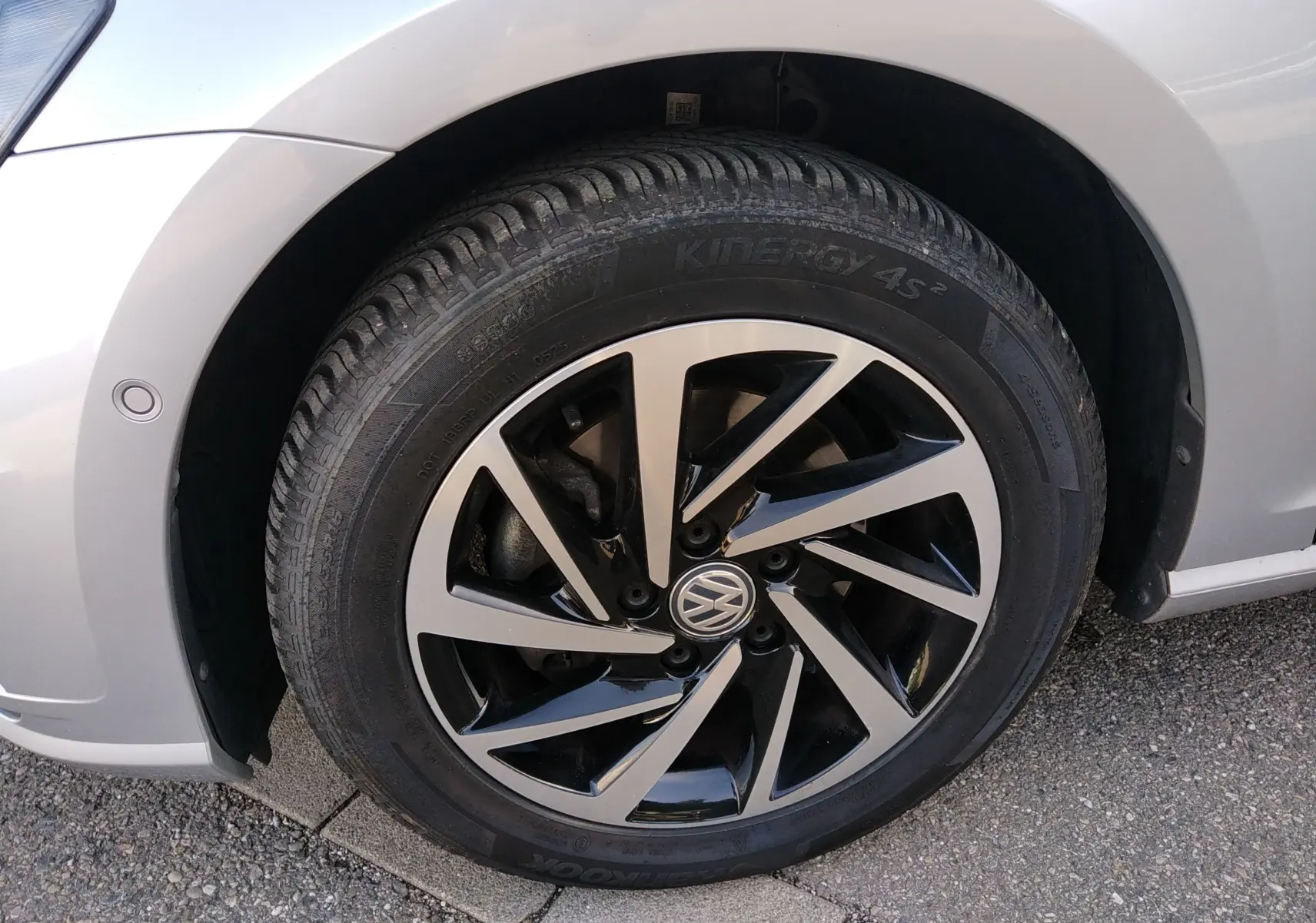 Gros plan sur la roue avant gauche d'une Volkswagen Golf gris reflet d'argent avec jante alliage noire et argentée.