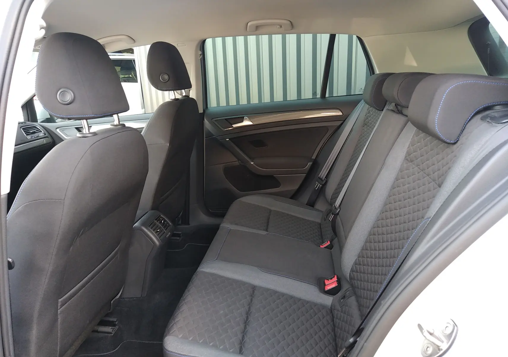 Vue intérieure côté droit des sièges arrière en tissu noir avec surpiqûres bleues d'une Volkswagen Golf 2019.