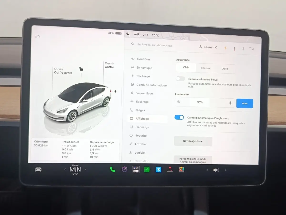 Écran tactile central affichant les réglages et la vue 3/4 avant d’une Tesla Model 3 blanche 2022 Grande Autonomie.