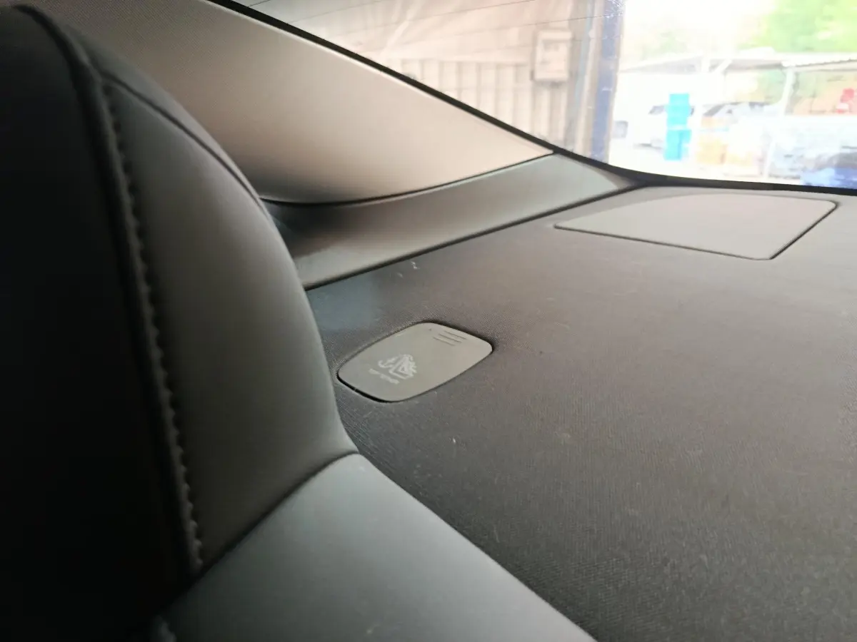Détail intérieur du tableau de bord noir de la Tesla Model 3 2022, avec zone de recharge par induction visible.