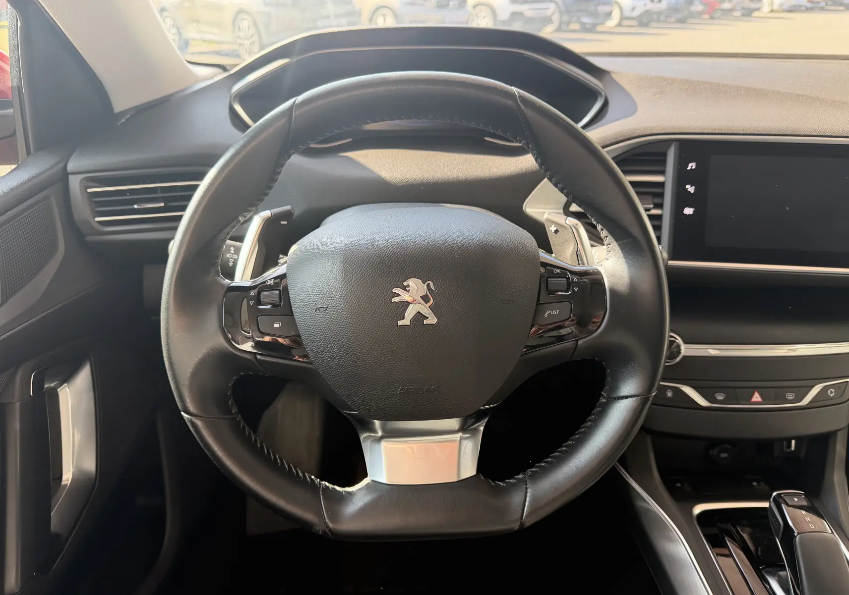 Vue intérieure centrée sur le volant cuir noir du Peugeot 308 SW 1.2T 130 Allure Pack avec tableau de bord moderne.
