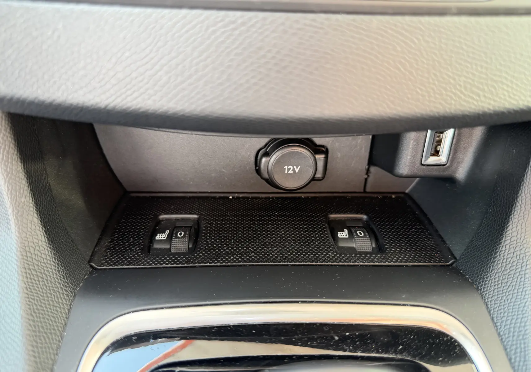 Gros plan sur les commandes de sièges chauffants et prise 12V dans l'habitacle du Peugeot 308 SW rouge rubis.