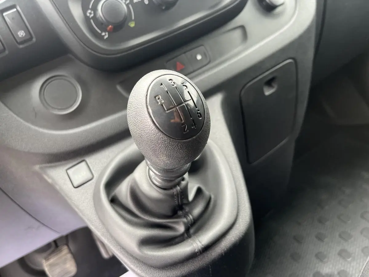 Le levier de vitesses manuel noir en gros plan dans l'habitacle du Renault Trafic Fourgon blanc de 2016.