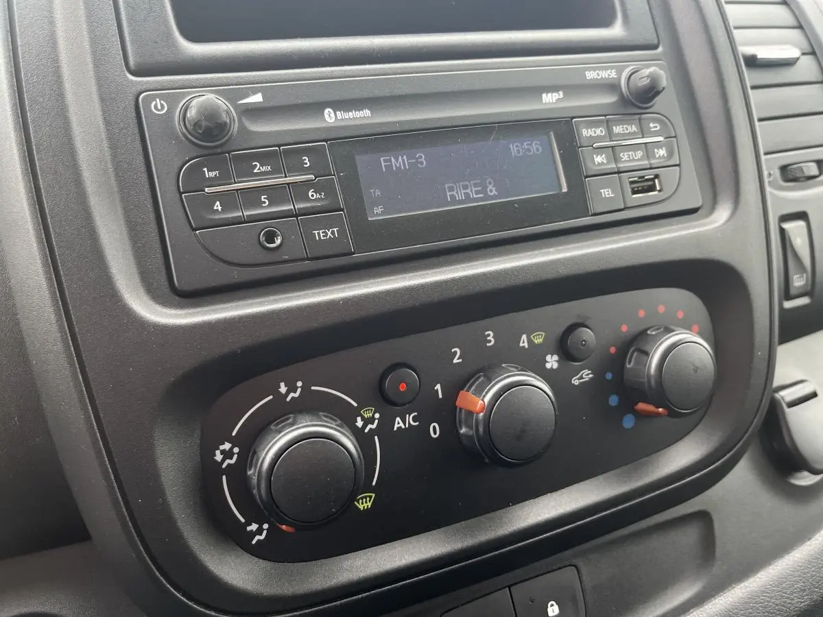 Tableau de bord noir du Renault Trafic Fourgon blanc 2016 montrant la radio et les commandes de climatisation.