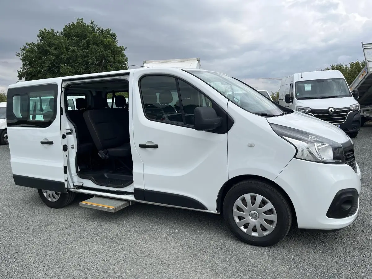Renault Trafic Fourgon blanc vu de profil droit avec porte latérale coulissante gauche ouverte et marchepied déployé.
