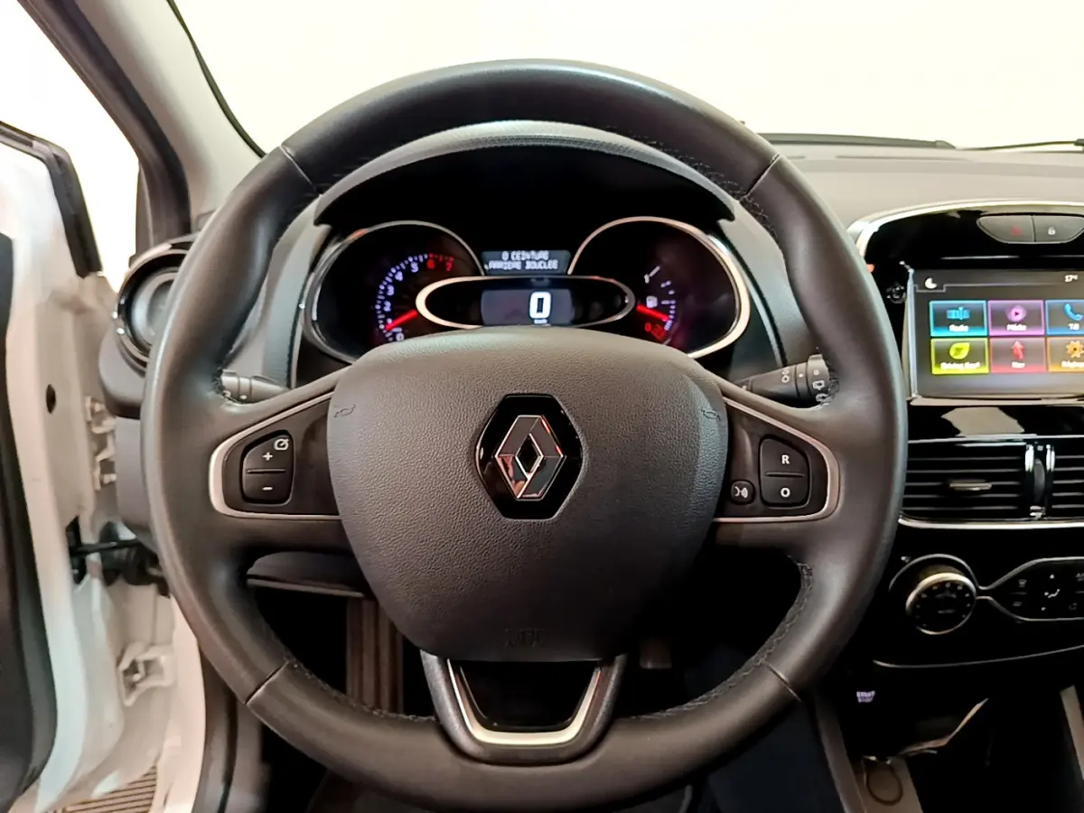 Vue intérieure centrée sur le volant cuir multifonctions d'une Renault Clio Business blanc avec tableau de bord et écran tactile.