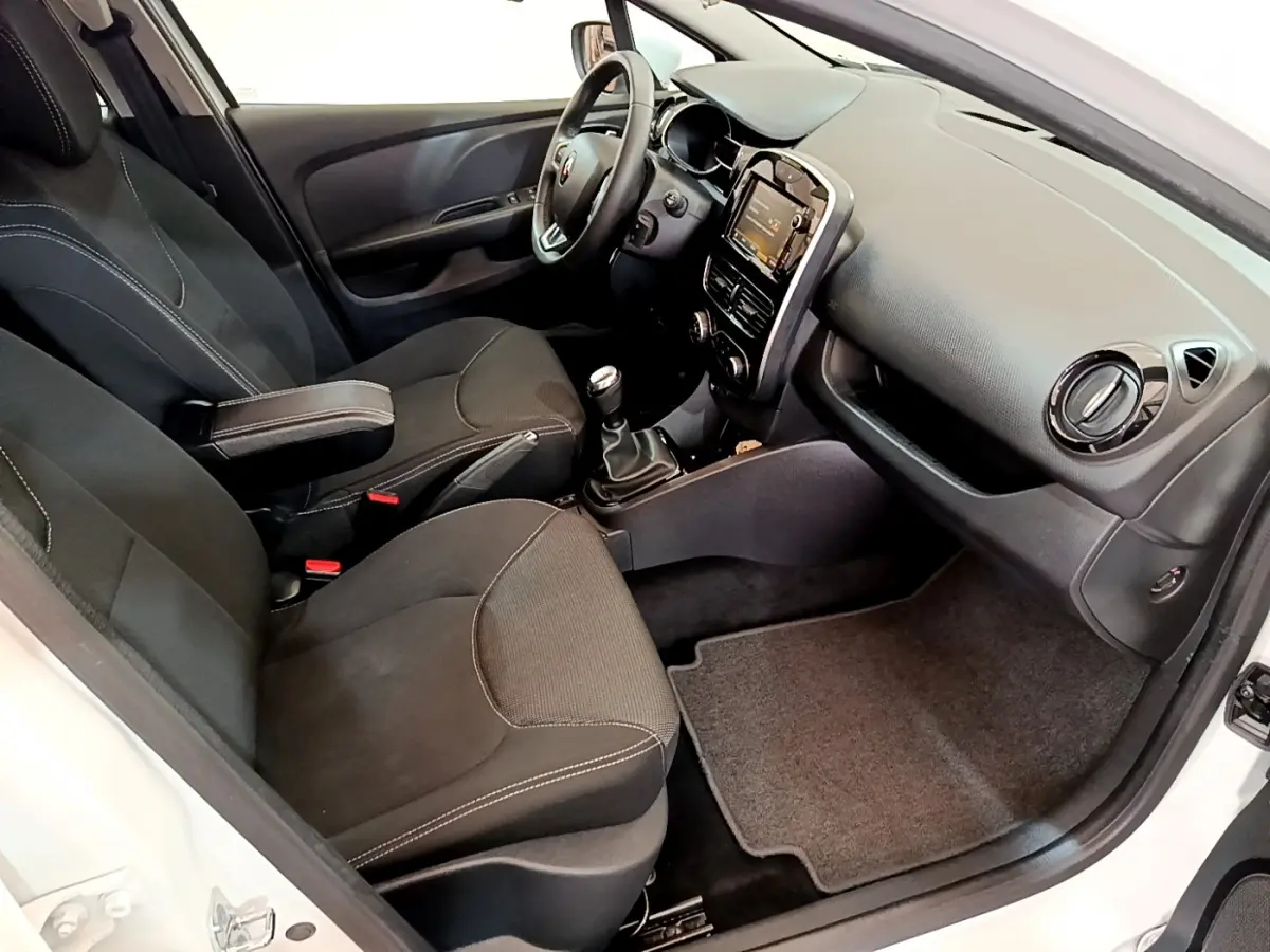 Intérieur de la Renault Clio Business blanc vue côté passager, montrant sièges noirs et tableau de bord avec écran tactile.