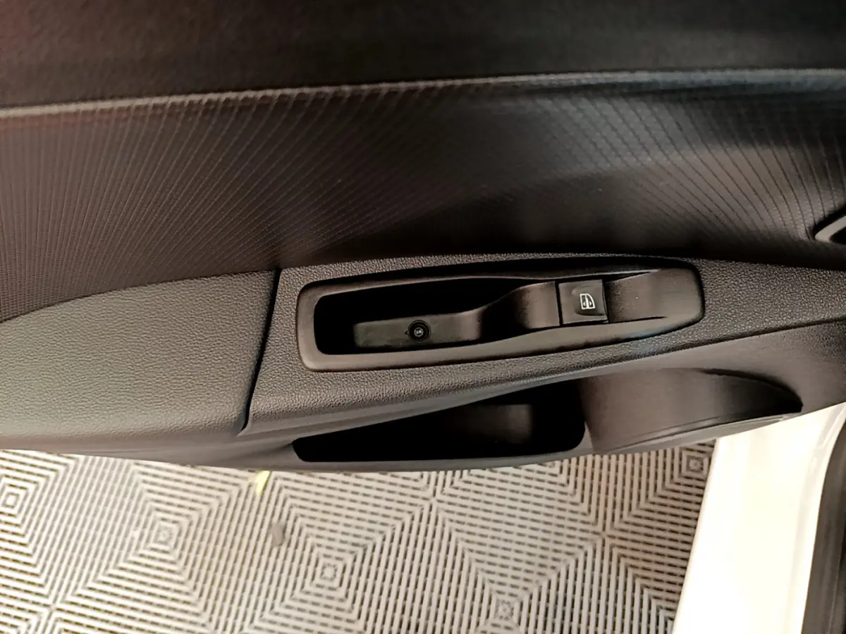 Détail de la commande de lève-vitre côté conducteur sur porte intérieure noire d'une Renault Clio Business blanche 2019.