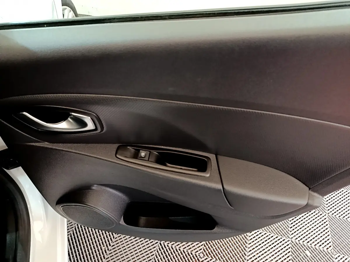 Vue rapprochée de la porte avant gauche blanche de la Renault Clio Business TCe 90 avec poignée et commande de fenêtre.