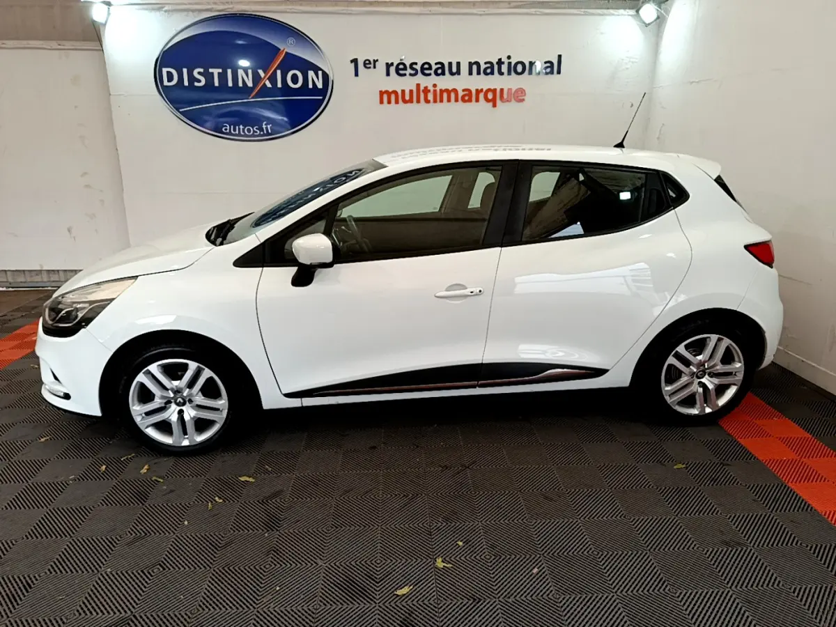 Profil côté gauche d'une Renault Clio Business TCe 90 blanche, avec jantes alliage et poignées de porte assorties.