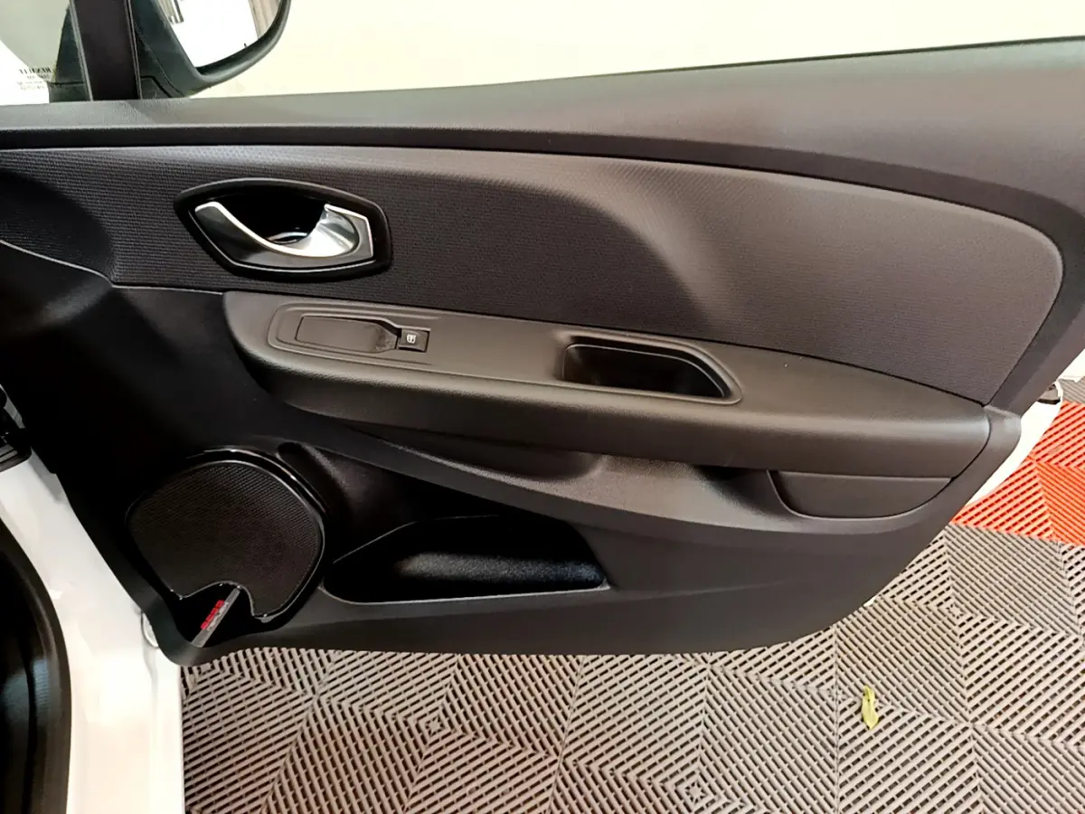 Gros plan sur la porte avant gauche noire de la Renault Clio Business blanche, avec poignée et haut-parleur intégrés.