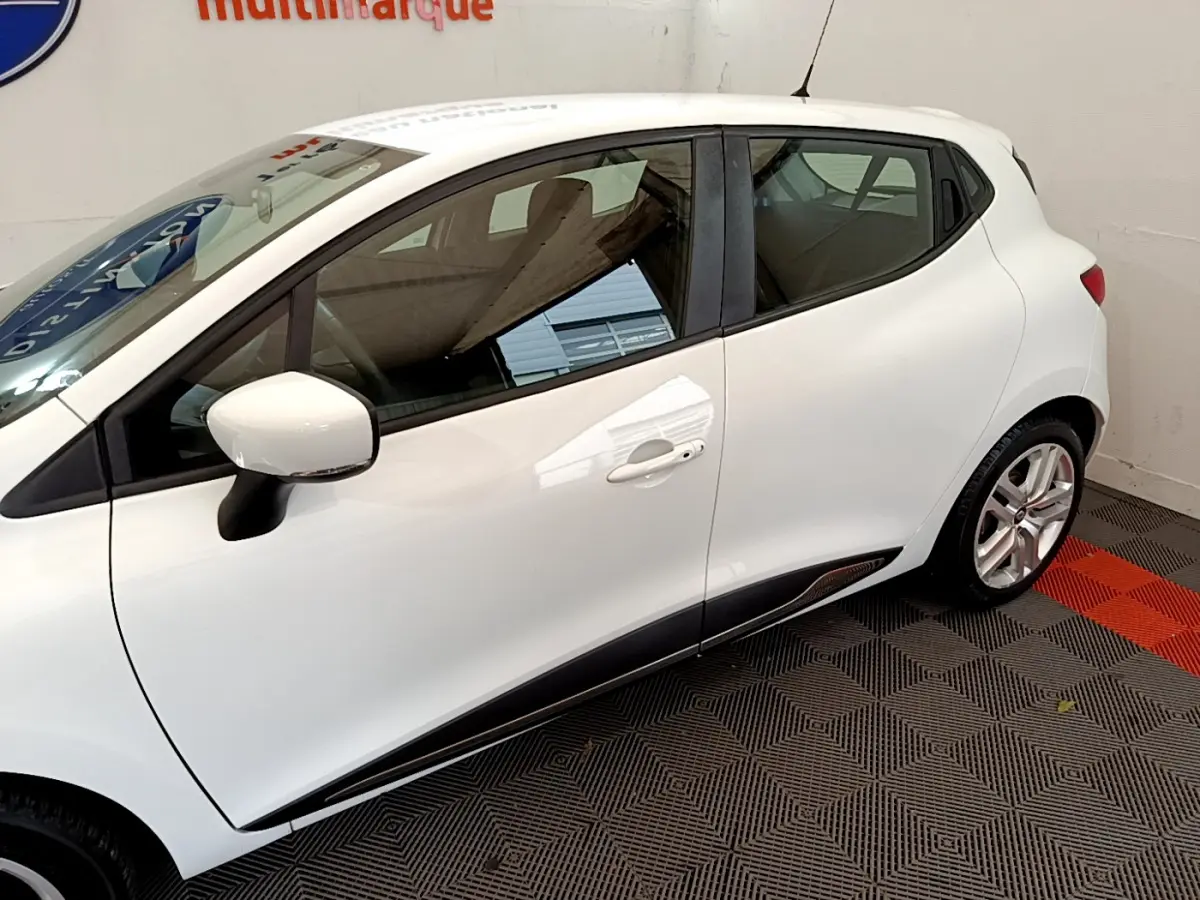 Profil côté gauche d'une Renault Clio Business TCe 90 blanche, avec poignées de porte intégrées et jantes alliage visibles.