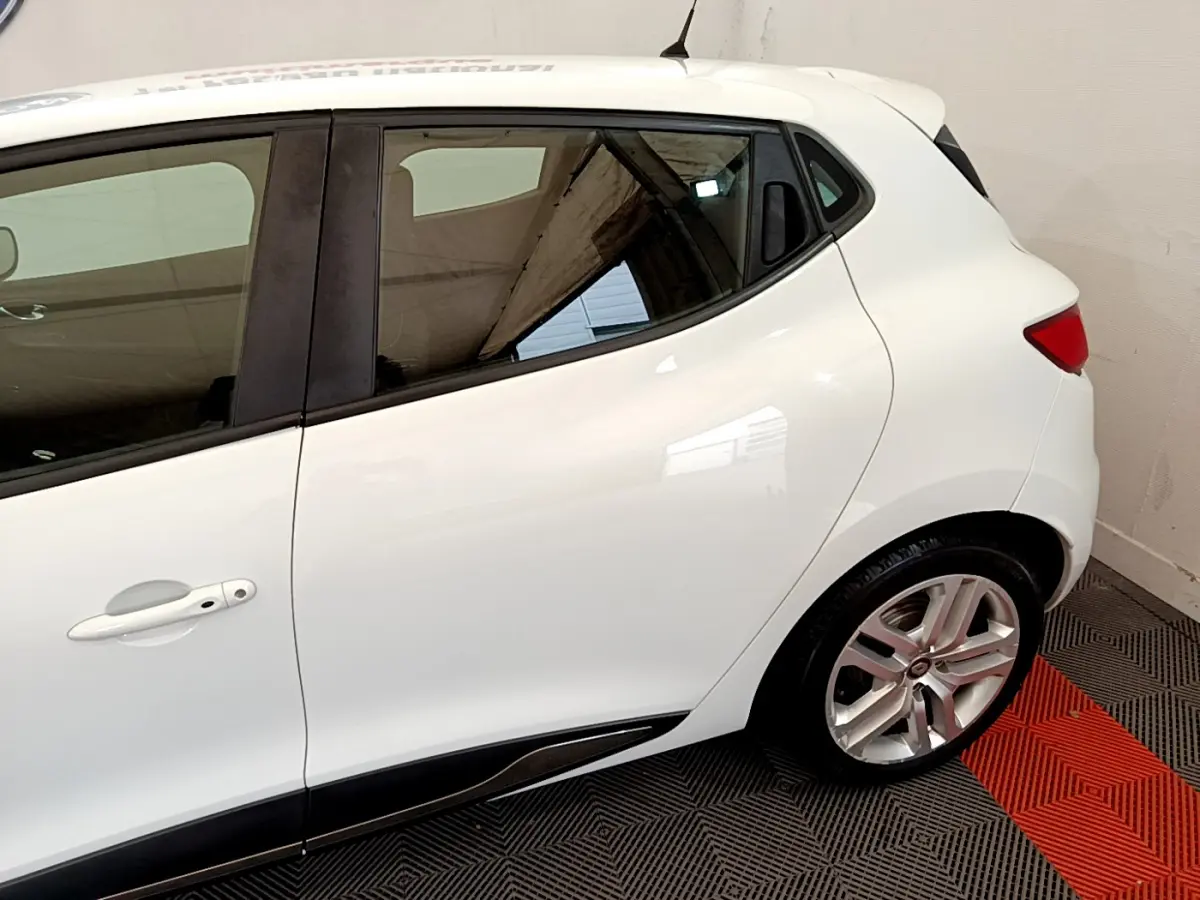 Profil côté gauche d'une Renault Clio Business TCe 90 blanche, mettant en valeur la porte arrière et la jante alliage.