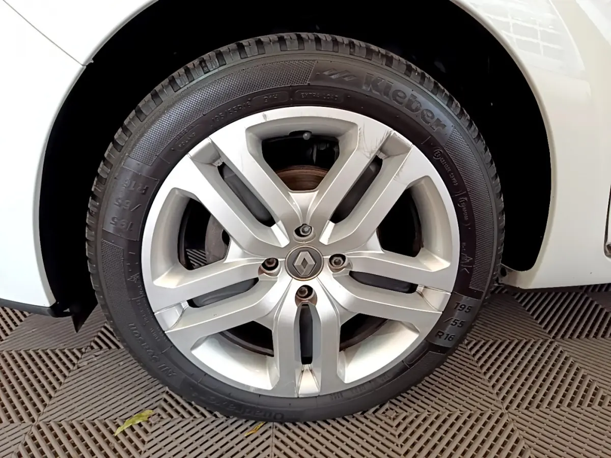 Gros plan sur la roue avant droite d'une Renault Clio Business blanche, jante alliage argentée avec logo Renault central.