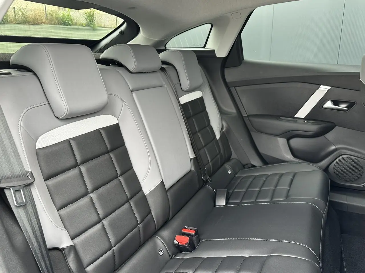 Vue intérieure côté droit des sièges arrière en cuir noir et gris clair du Citroën C4 NV Hybrid 2025 avec finitions contrastées.