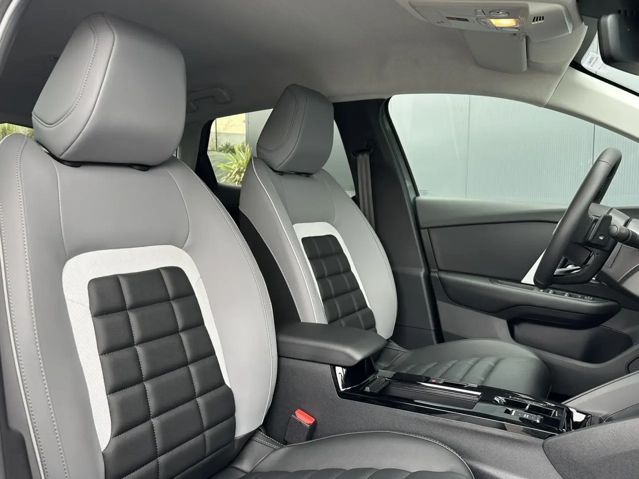 Vue intérieure côté conducteur de la Citroën C4 2025, sièges Advanced Comfort gris et noir avec accoudoir central.