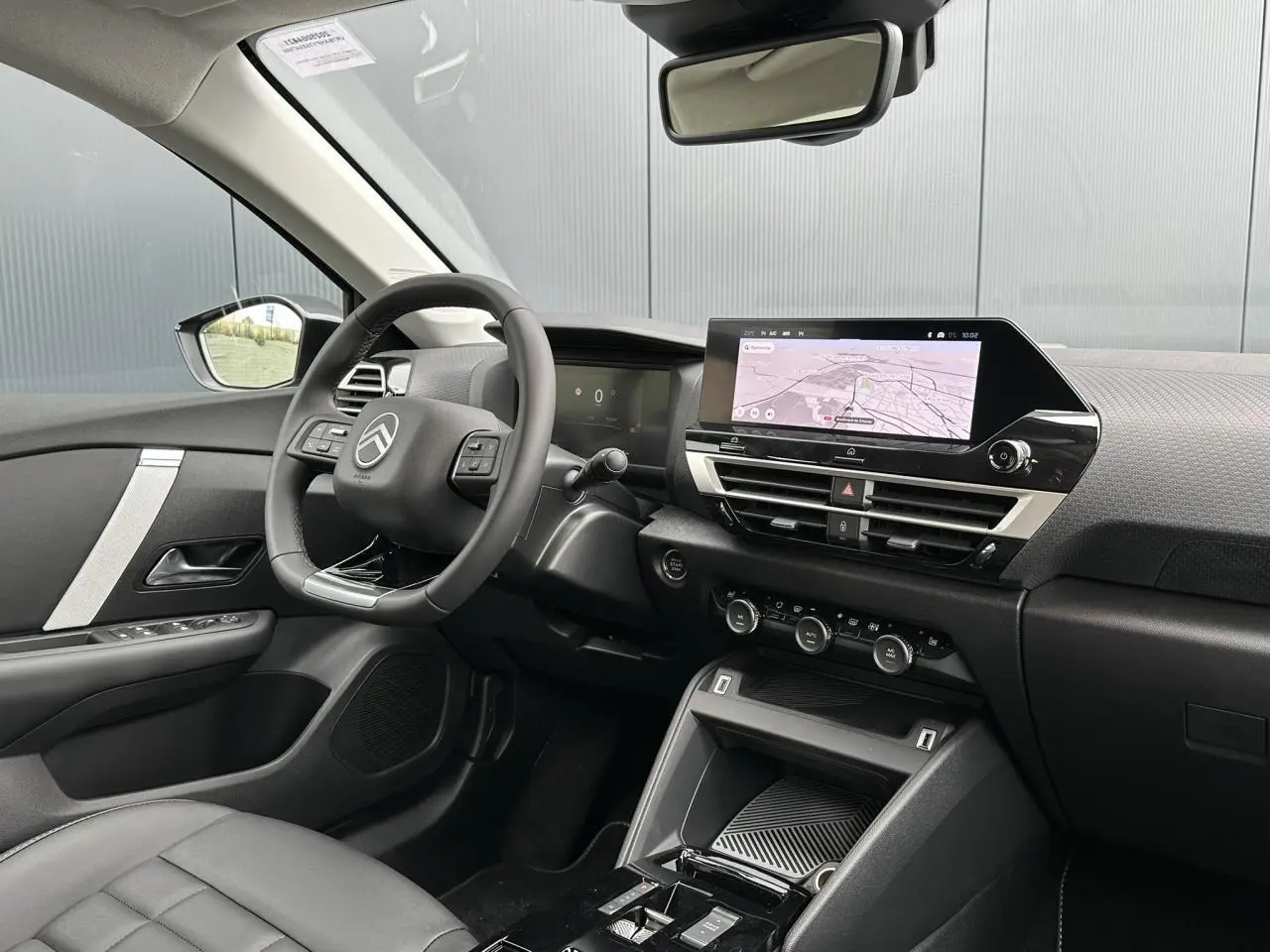 Intérieur avant droit de la Citroën C4 Manhattan Green 2025, avec écran tactile GPS et volant cuir noir.