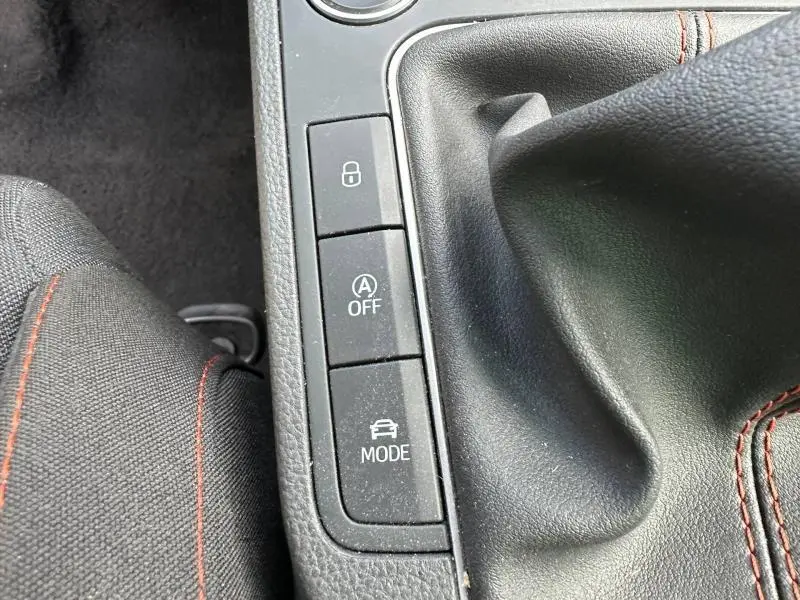 Gros plan sur la console centrale de la SEAT Ibiza 2025, montrant les boutons de verrouillage, mode et arrêt auto start-stop, avec surpiqûres rouges.