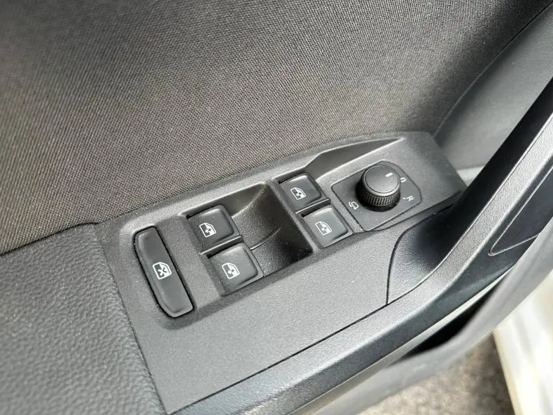 Gros plan sur les commandes de lève-vitres et réglage des rétroviseurs côté conducteur d'une SEAT Ibiza 2025 blanc Nevada métal.