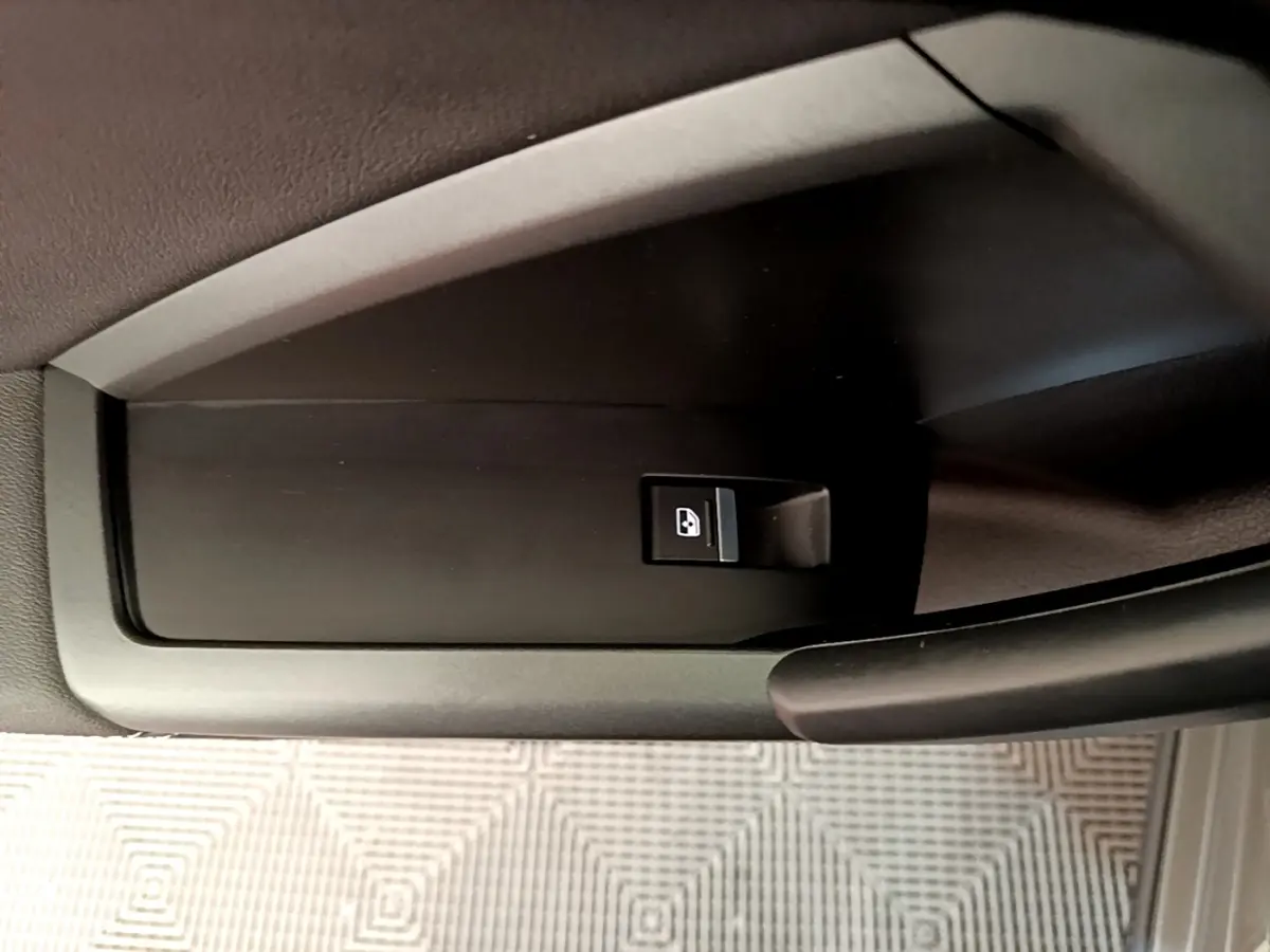 Bouton de commande de lève-vitre sur la portière côté conducteur de l'Audi Q3 gris foncé, vue rapprochée intérieure.