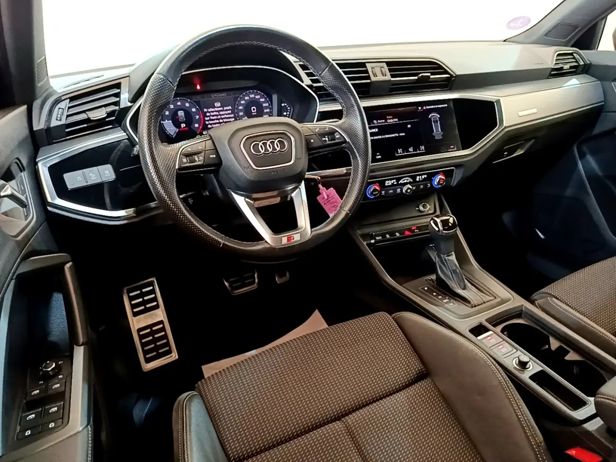 Vue intérieure côté conducteur de l'Audi Q3 35 TFSI S Line 2021, volant cuir multifonctions et tableau de bord digital.