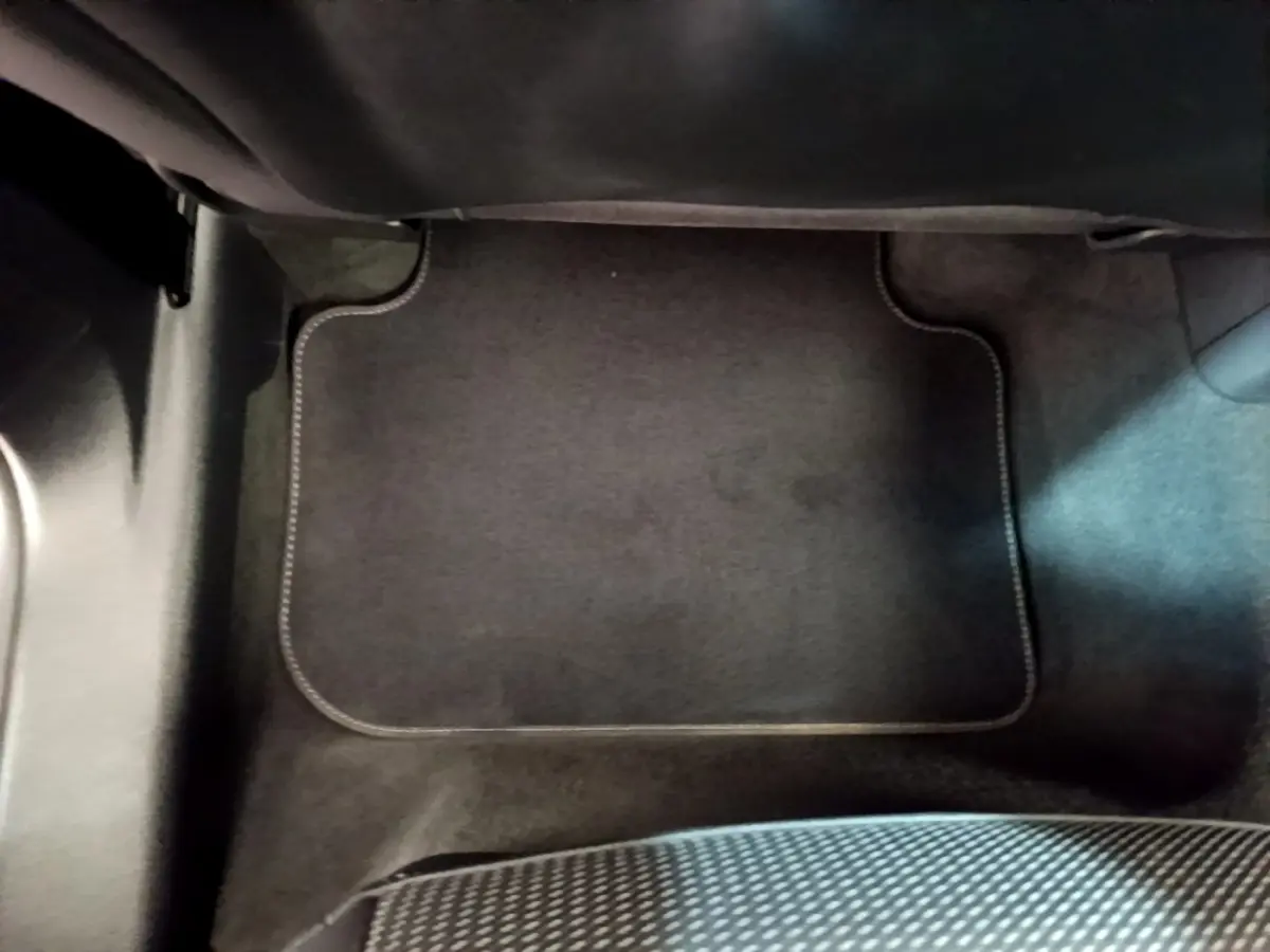 Tapis de sol noir côté passager avant dans un Audi Q3 gris foncé, vue rapprochée de l'intérieur.