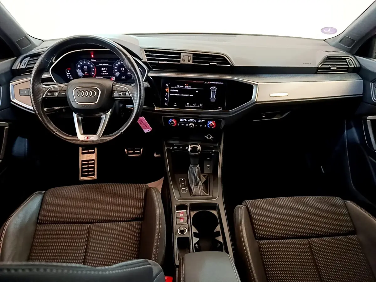 Vue intérieure avant de l'Audi Q3 35 TFSI S Line 2021, avec tableau de bord numérique et volant cuir multifonctions.
