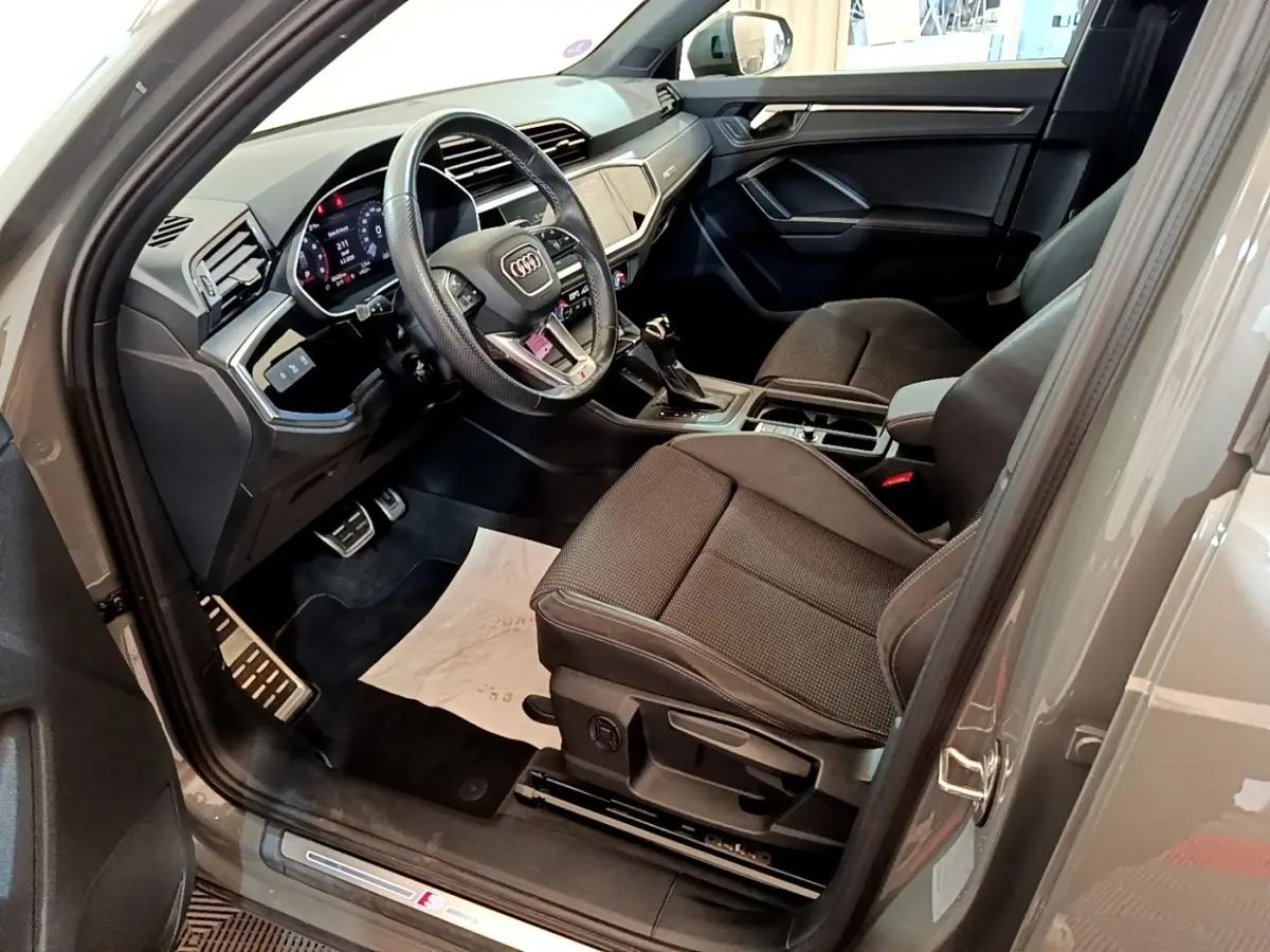Intérieur Audi Q3 35 TFSI S line 2021 gris foncé, vue côté conducteur avec volant cuir multifonctions et tableau de bord digital.