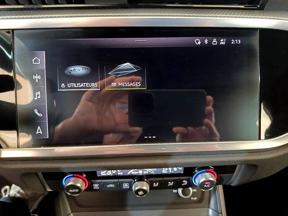 Écran tactile central et commandes climatisation du tableau de bord de l'Audi Q3 gris foncé, vue intérieure frontale.