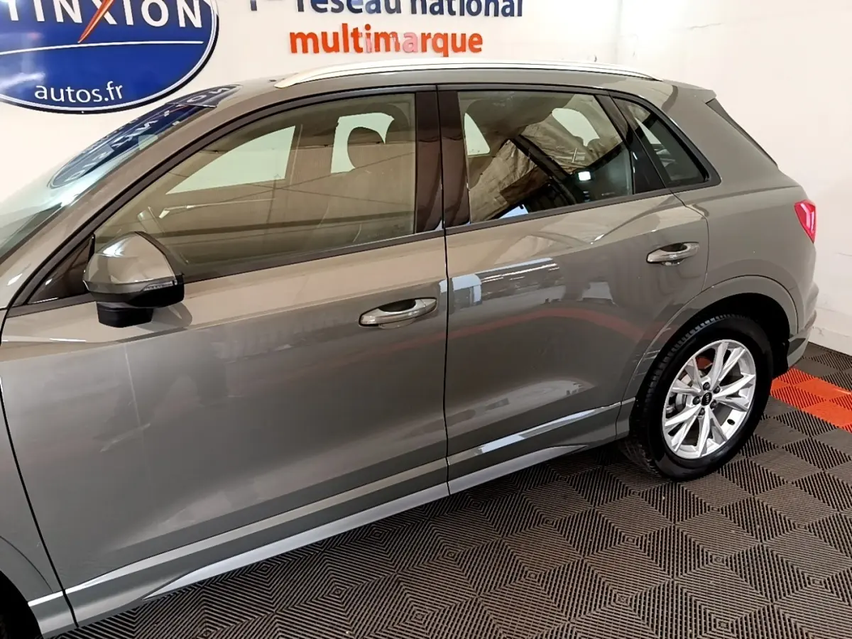 Vue latérale côté gauche d'un Audi Q3 gris foncé 35 TFSI 150 MHEV S Line avec jantes alliage et rétroviseurs assortis.