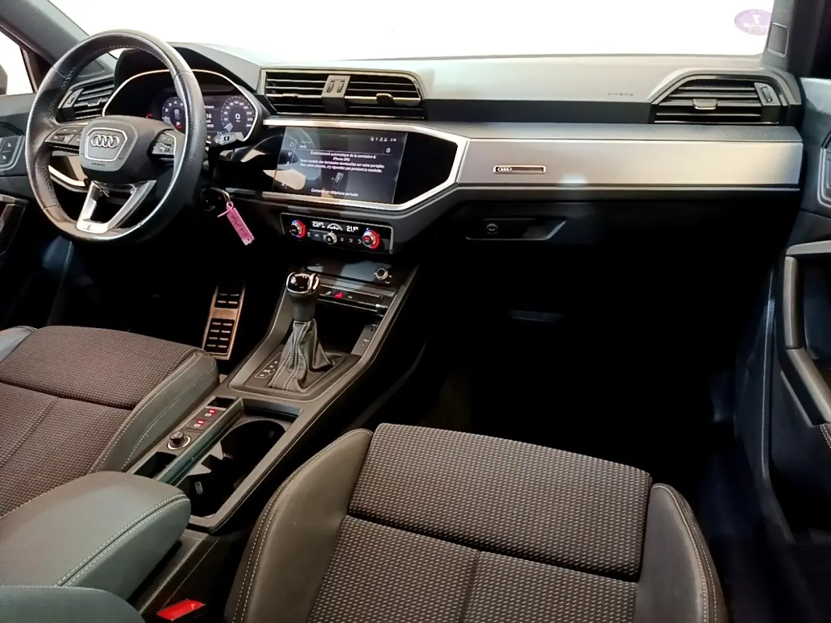 Vue intérieure avant droite de l'Audi Q3 35 TFSI S Line 2021 avec tableau de bord gris clair et volant cuir multifonctions.