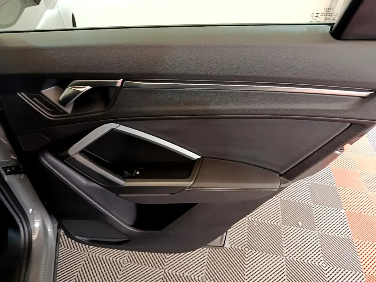 Vue rapprochée de la porte avant gauche gris foncé d’un Audi Q3 35 TFSI S Line avec poignée et garniture noire.